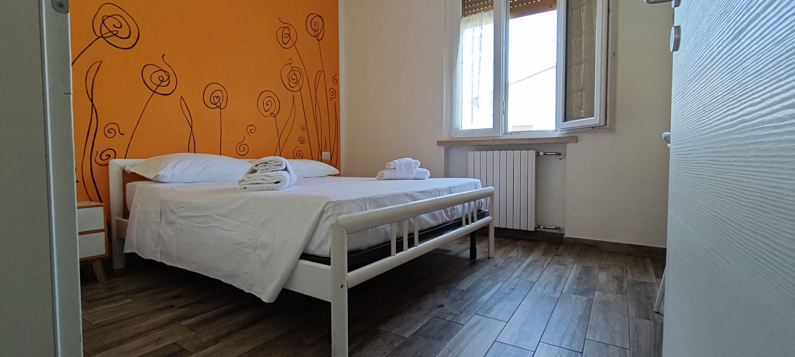 Appartamento 3.Arancio — camera matrimoniale con parete arancio e finestra