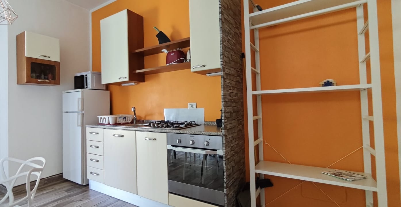 Appartamento 3.Arancio — cucina completa con colonna e mensole a giorno