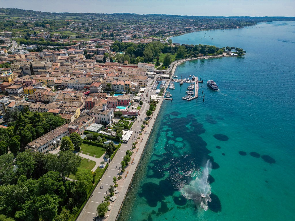 Vista aerea del lungolago di Bardolino sul Lago di Garda, con porto, promenade e tetti in coppi