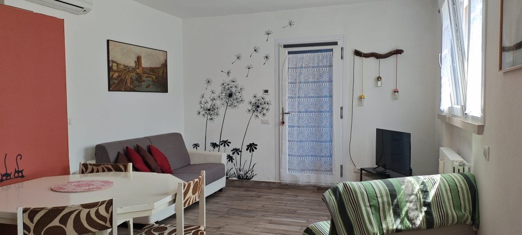 Appartamento 2.Rosso — zona giorno con divani, tavolo e Smart TV